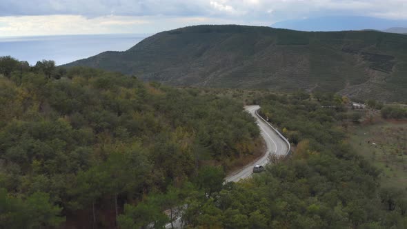 Aerial Landscape Suv Car Traveling on Serpentine Road Among Green Pastures and Mountains