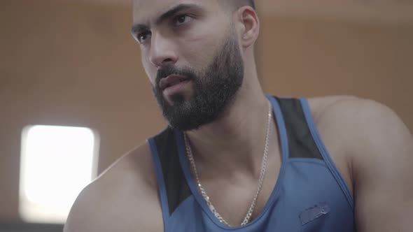 Close-up Face of Confident Handsome Sportsman Looking at Biceps As Lifting Dumbbell Weights