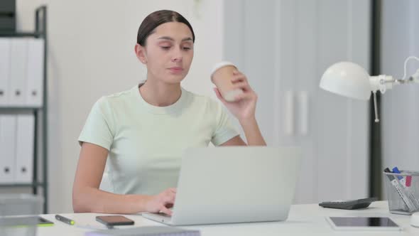 Young Latin Woman Drinking Coffee and Working on Laptop