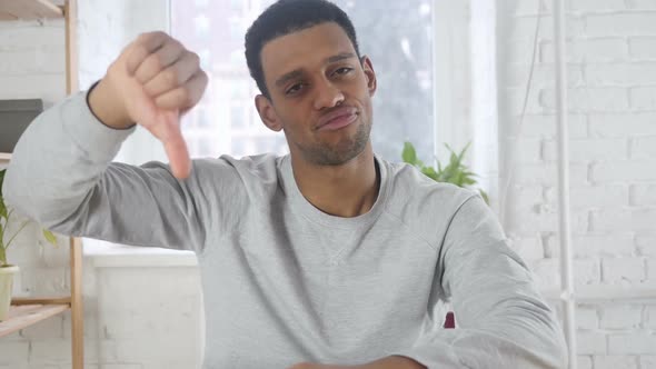 Portrait of AfroAmerican Man Gesturing Thumbs Down Indoor