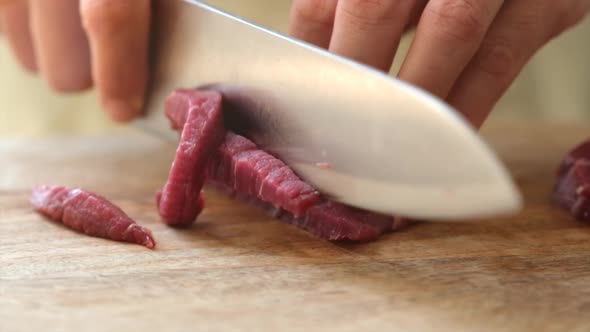 Crop woman cutting meat in kitchen