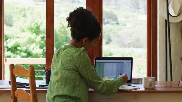 Mixed race woman taking notes while working from home