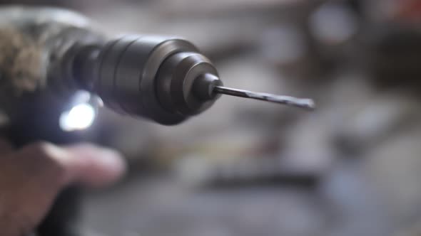 Spinning drill bit in males hand close up