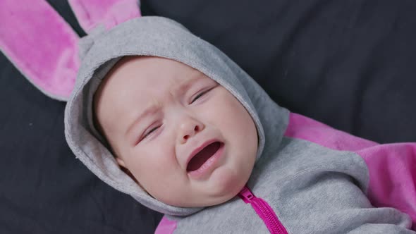 A Baby Lies on the Bed and Cries. Child Is Upset and Crying.