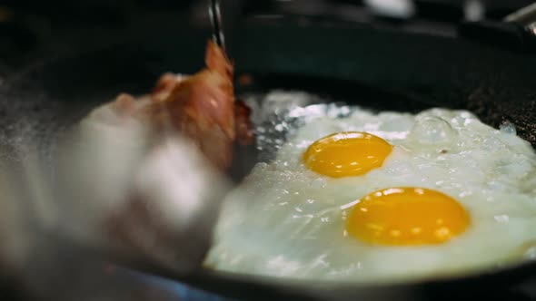 Cooking Delicious Fried Eggs with Bacon in Pan.