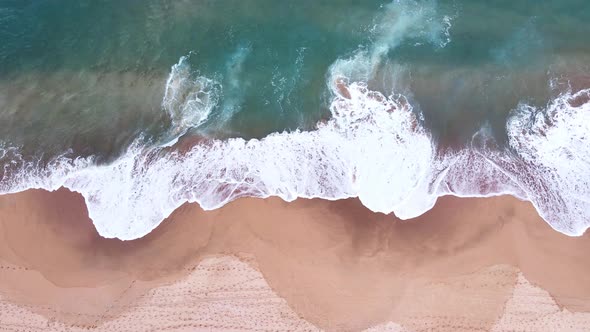 Aerial Top View of Ocean Waves Reaching Beach Shore. Drone Footage.