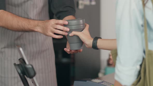 Young Asian male bartender giving drink coffee cup to beautiful Korean girl customer.