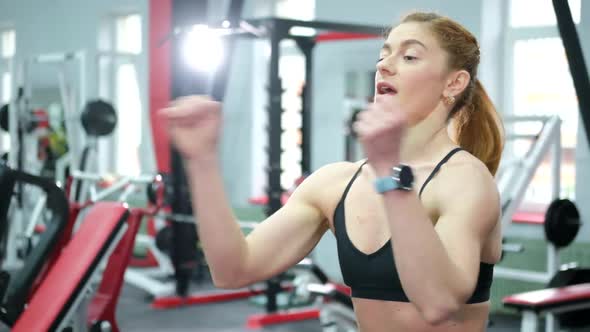 Fitness a Muscular Female Athlete Trains in the Gym with Heavy Dumbbells