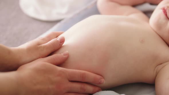 Mother Massaging Baby Tummy. Baby Skin Care and Development Concept