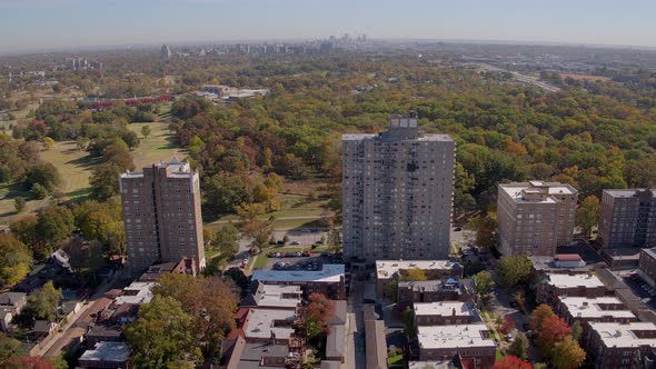 Drone pulls away from Apartment buildings to reveal a historic neighborhood district and park urban