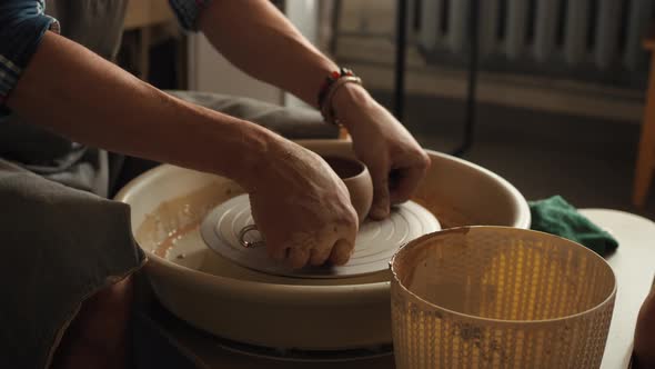Closeup Shot of Ceramic Cup Spinning on Potters's Wheel and Hands Molding Clay