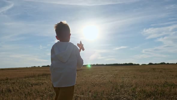 Boy Runs in Field with Toy Plane in Hand and Flies Airplane
