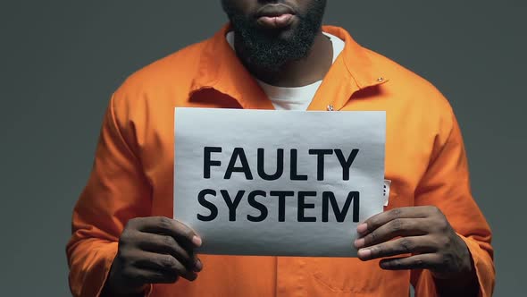 Faulty System Phrase on Cardboard in Hands of Afro-American Prisoner, Disorder