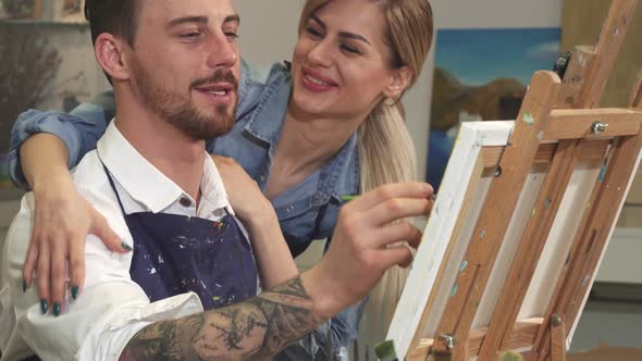 Professional Artist Painting on Canvas His Girlfriend Hugging Him