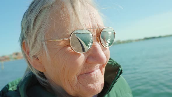 Greyhaired Woman in Sunglasses Stands Against Venice Lagoon