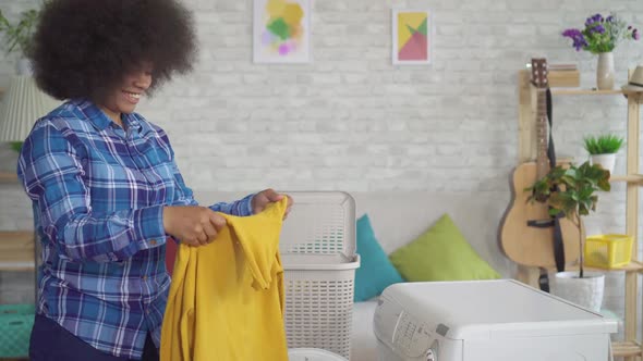 Portrait African American Housewife in Shirt Doing Homework Taking Out Washed Clothes at Home