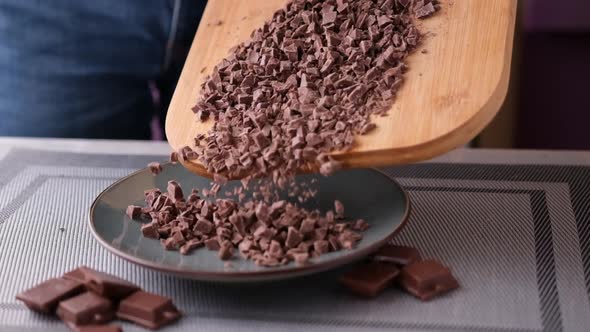 Woman Pouring Chopped Black Dark Chocolate From Wooden Cutting Board to Plate