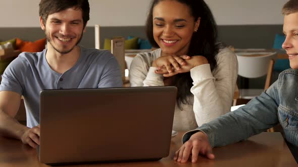 Young People Smiling About What They See on Laptop at the Cafe