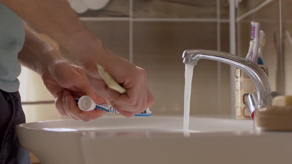 Young Man Squeezing Toothpaste Onto a Brush