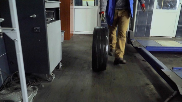 Worker rolls a wheel in a car repair shop