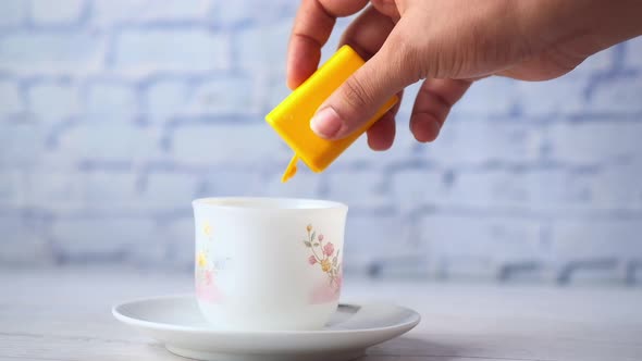 Young Women Putting Artificial Sweetener in Tea