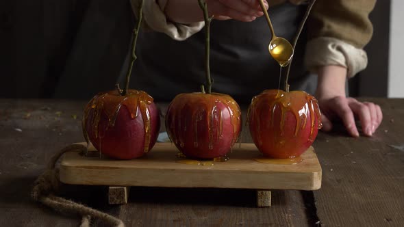 woman pouring caramel over three apples