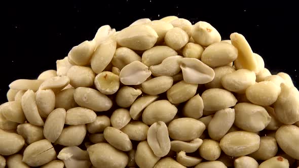 Falling blanched peanuts on a black background.