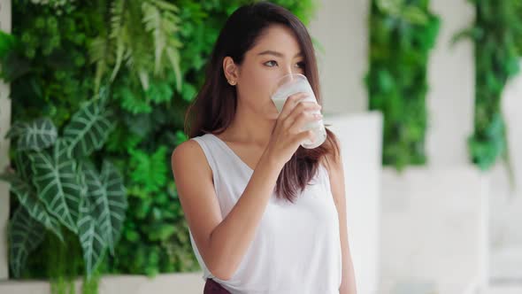 Attractive Asian woman drinking milk and smiling at home close up face.healthy