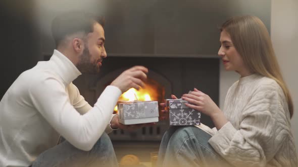 Romantic Holiday Cheerful Guy and a Female Give Each Other Boxes with Gifts a Young Couple is