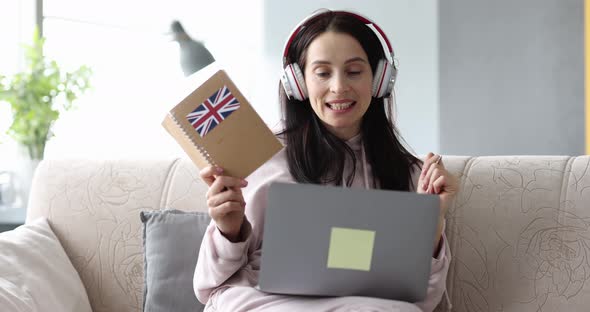 Woman in Headphones is Learning British English Remotely on Laptop alt