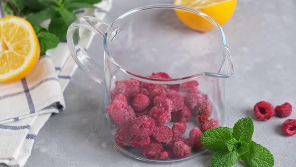 Delicious raspberry tea brewed in big glass teapot standing on a light background