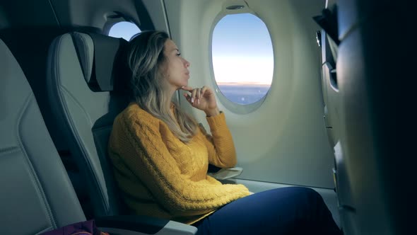 A Lady Is Looking at the Sunrise in the Airplane Window