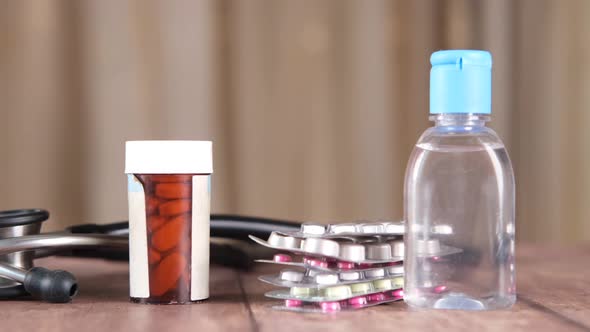 Hand Sanitizer Stethoscope and Pills Container on Wooden Background