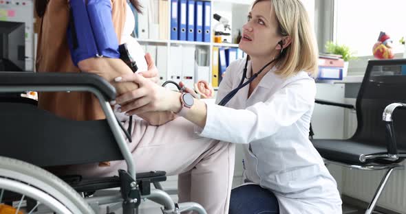 Doctor Listens with Stethoscope to Belly of Pregnant Woman in Wheelchair