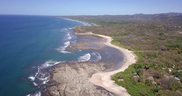 Aerial drone view of the beach, rocks and tide pools in Playa Palada, Guiones, Nosara, Costa Rica.