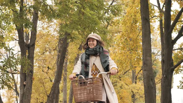 A Young Beautiful Woman Rides a Bicycle Through the Autumn Park