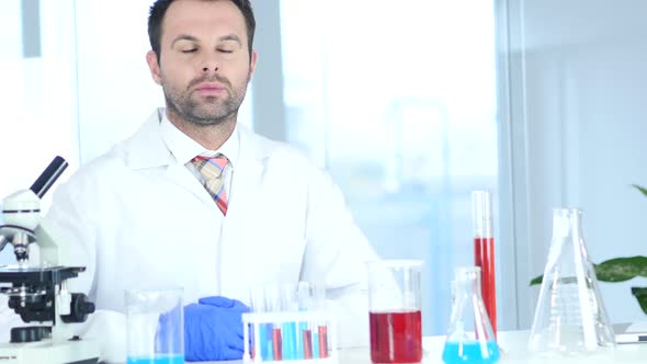 Serious Scientist Sitting in Chemical Laboratory Microscope