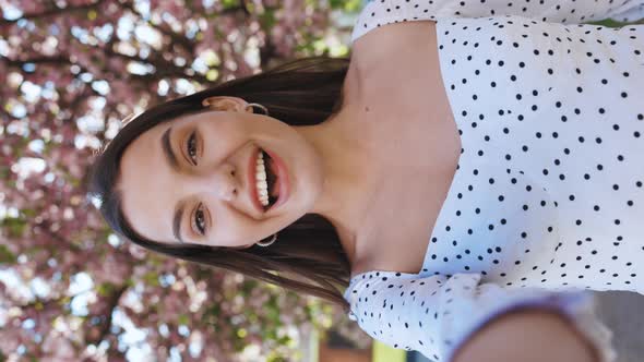 Vertical Video of Smiling Girl Having Video Call on Smartphone in City Park