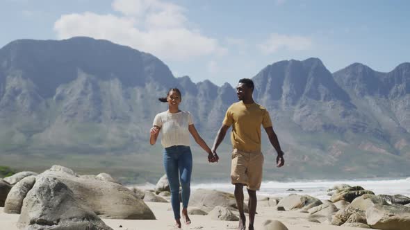 African american couple holdings hands and walking at the beach