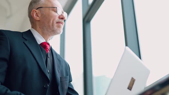 Mature businessman in glasses using laptop