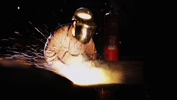 Steel Mill Worker cutting Steel Bar with Blow Torch.