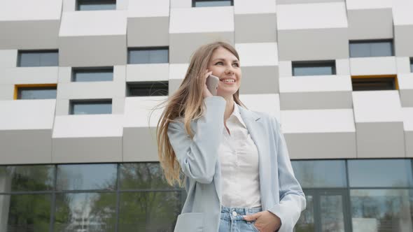 Caucasian Confident Young Business Woman in White Shirt is Talking on Phone