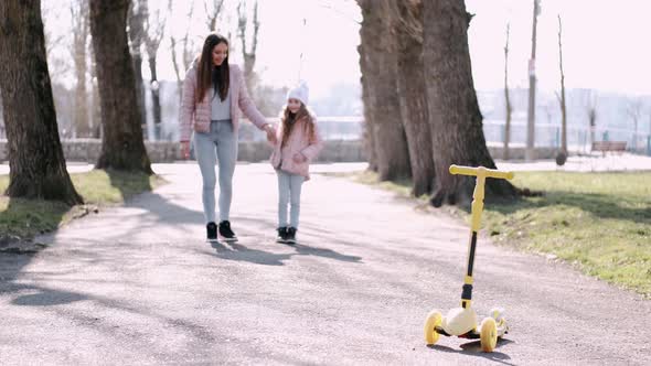 The Mother and Cute Daughter Are Walking in the Park