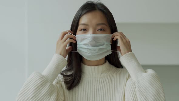 Young Asian Woman Puts on a Medical Protective Facial Mask Against Virus and Infection Diseases