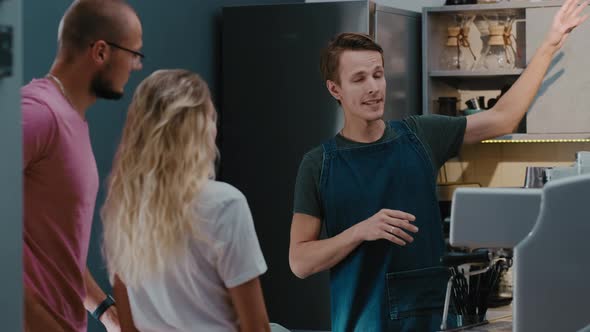 Back view of customers couple making order or buying coffee from barista in  stylish coffee shop