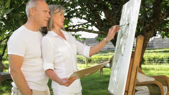 Mature couple painting in domestic garden