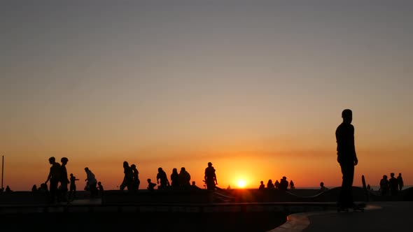 Silhouette of Young Jumping Skateboarder Riding Longboard, Summer Sunset Background. Venice Ocean