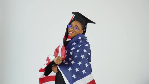 Happy Stylish Afro American Female Student in Graduate Uniform Dancing Holding Usa Flag Over