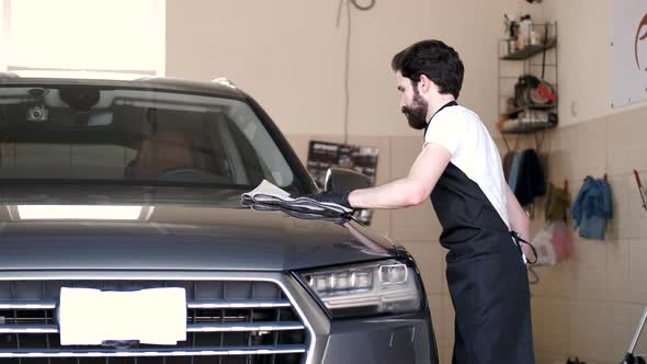 Man Wipes a Car in a Garage