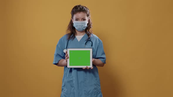 Portrait of Woman Doctor Holding Tablet Computer with Green Screen Wearing Hospital Uniform and